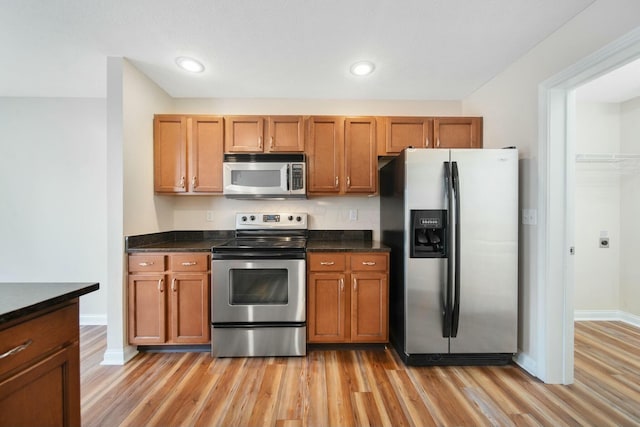 kitchen featuring stainless steel appliances, brown cabinetry, and light wood-type flooring