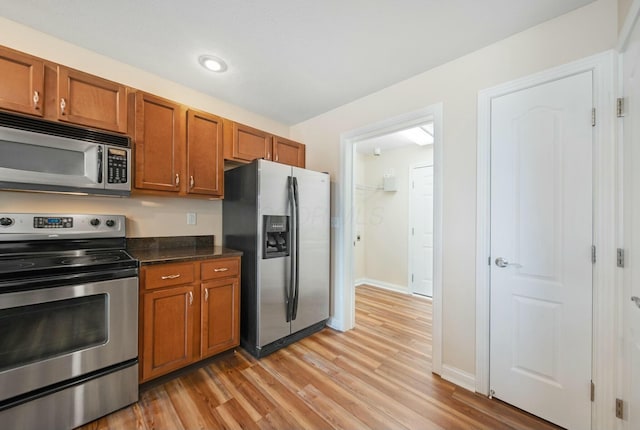 kitchen with brown cabinets, light wood-type flooring, baseboards, and stainless steel appliances