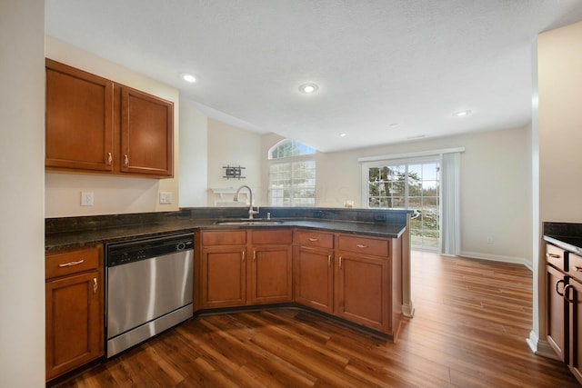 kitchen featuring dark wood-style floors, a peninsula, stainless steel dishwasher, and a sink