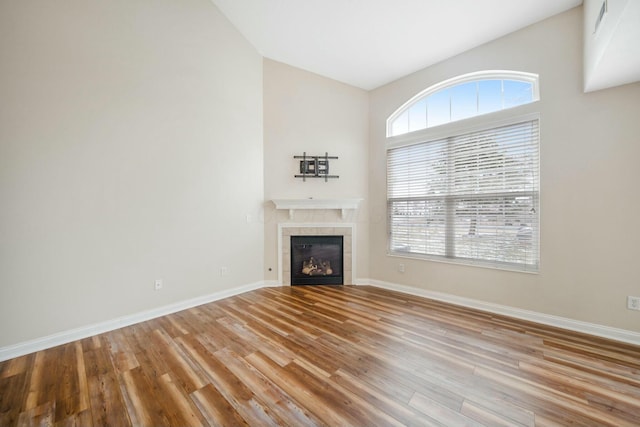 unfurnished living room with a wealth of natural light, a fireplace, baseboards, and wood finished floors