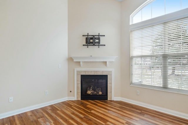 unfurnished living room featuring a fireplace, baseboards, and wood finished floors