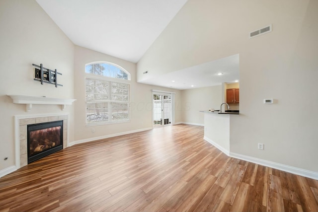 unfurnished living room with light wood-type flooring, a fireplace, visible vents, and baseboards