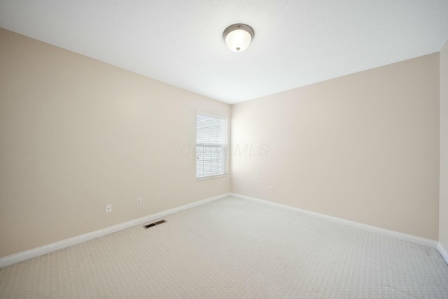 empty room with light colored carpet, visible vents, and baseboards