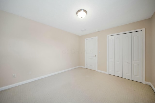 unfurnished bedroom with light carpet, a closet, and baseboards