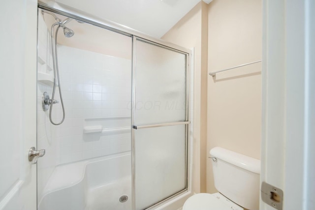 full bath featuring toilet and a shower with shower door