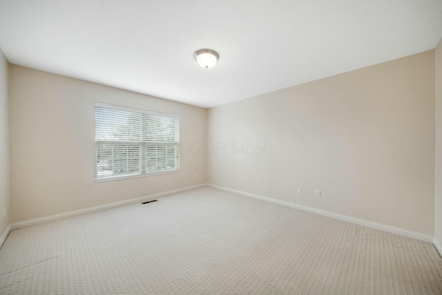 spare room with carpet flooring, visible vents, and baseboards