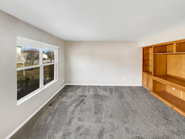 unfurnished room featuring visible vents, dark carpet, and baseboards