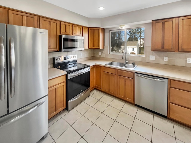 kitchen with appliances with stainless steel finishes, light countertops, a sink, and decorative backsplash