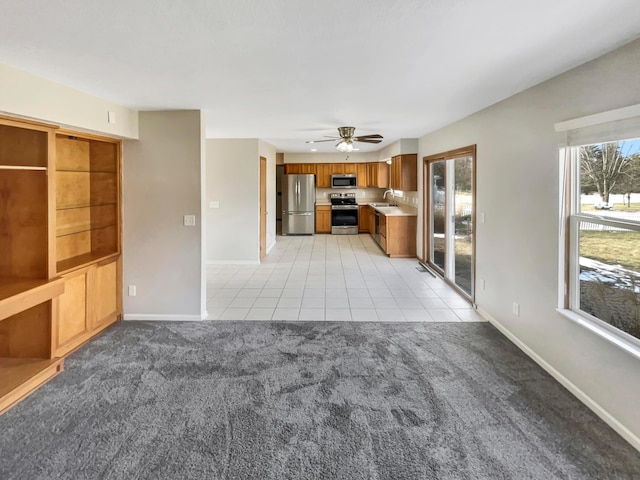 unfurnished living room with light carpet, a wealth of natural light, and baseboards