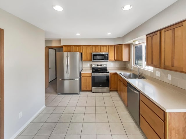 kitchen with light tile patterned floors, decorative backsplash, stainless steel appliances, light countertops, and a sink