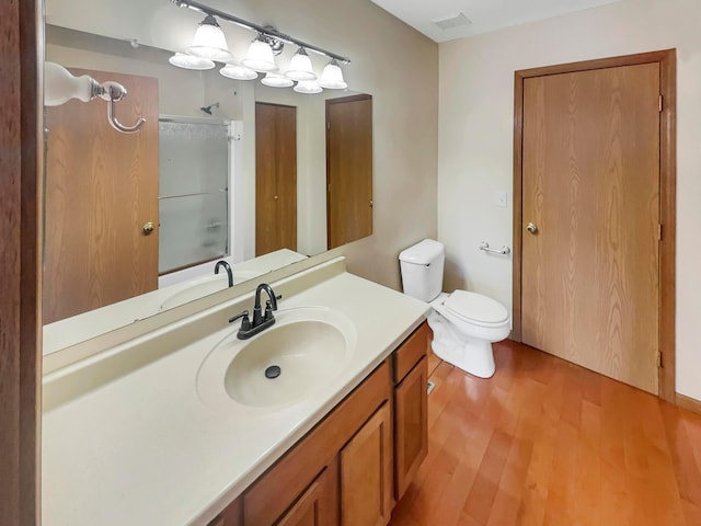 full bathroom with toilet, wood finished floors, vanity, visible vents, and walk in shower