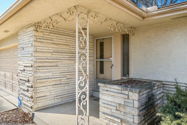 doorway to property featuring an attached garage and stucco siding