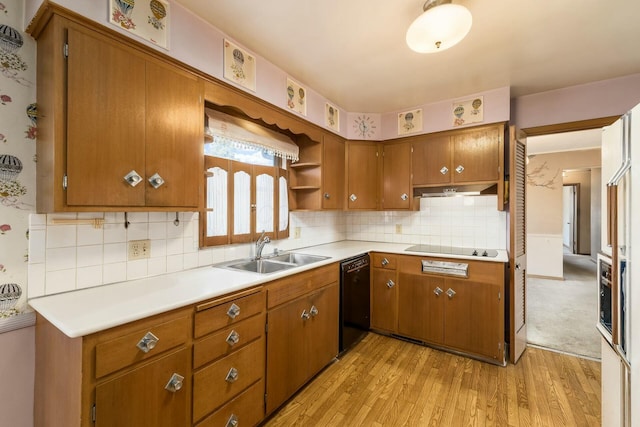 kitchen with under cabinet range hood, a sink, light countertops, black appliances, and light wood finished floors