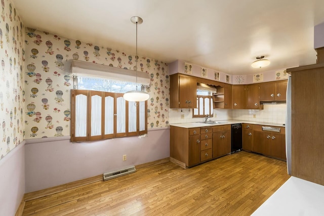 kitchen featuring brown cabinets, light wood finished floors, light countertops, visible vents, and wallpapered walls