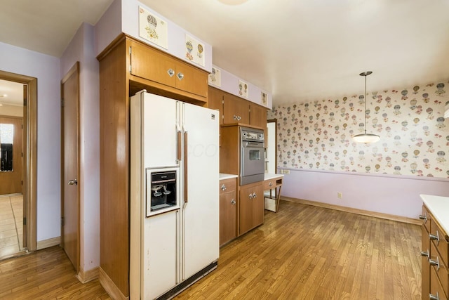 kitchen featuring light wood-style flooring, oven, white refrigerator with ice dispenser, light countertops, and brown cabinetry