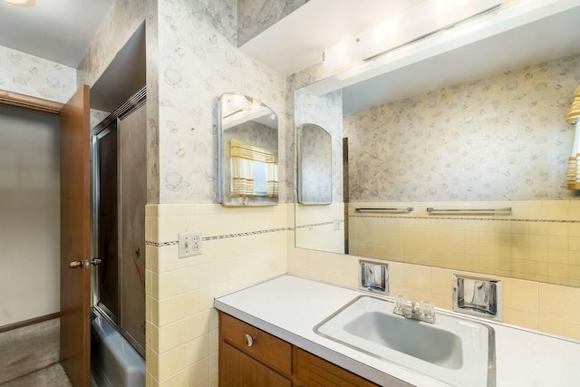 bathroom with a wainscoted wall, a tub to relax in, vanity, and wallpapered walls