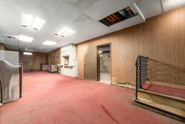 finished basement with wood walls, a drop ceiling, carpet flooring, and visible vents