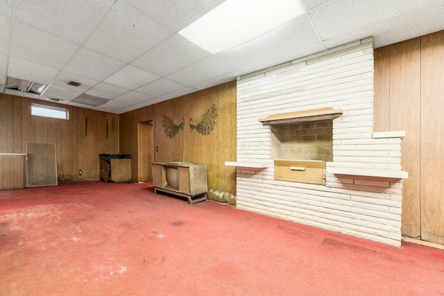 interior space featuring carpet floors, a paneled ceiling, visible vents, and wooden walls