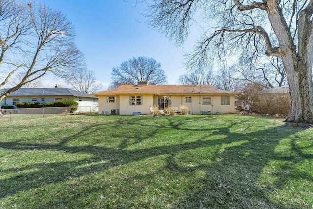 rear view of house with a chimney, fence, a lawn, and stucco siding