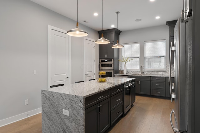 kitchen featuring light wood finished floors, appliances with stainless steel finishes, a kitchen island, and baseboards