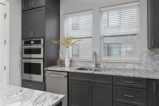 kitchen featuring tasteful backsplash, gray cabinets, appliances with stainless steel finishes, and a sink