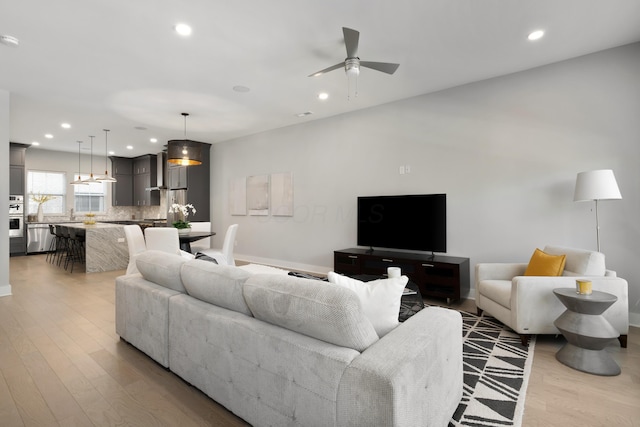 living room with a ceiling fan, recessed lighting, light wood-style floors, and baseboards