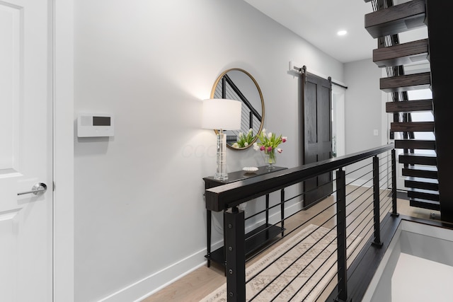 hall with baseboards, a barn door, an upstairs landing, recessed lighting, and wood finished floors