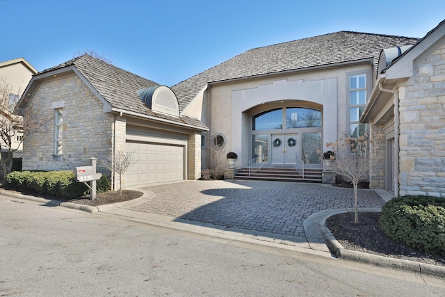 view of front of home with a garage, decorative driveway, french doors, and stone siding