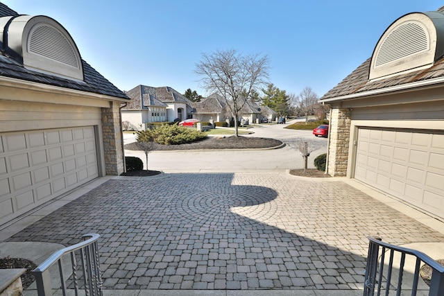 garage with decorative driveway and a residential view