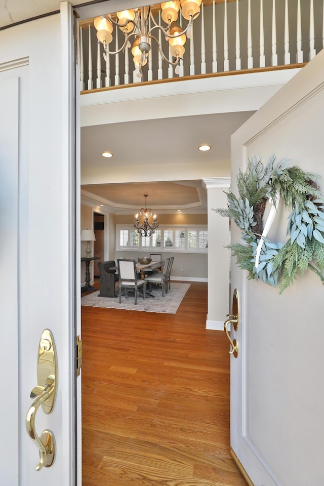 foyer entrance with a notable chandelier, baseboards, crown molding, and light wood-style floors