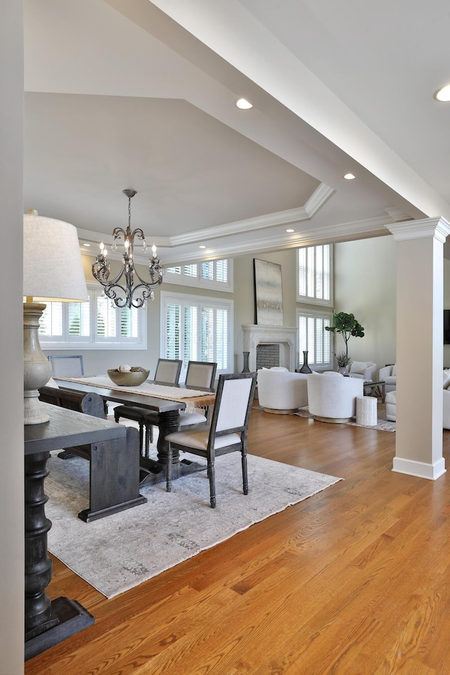 dining area with a raised ceiling, plenty of natural light, wood finished floors, and ornamental molding