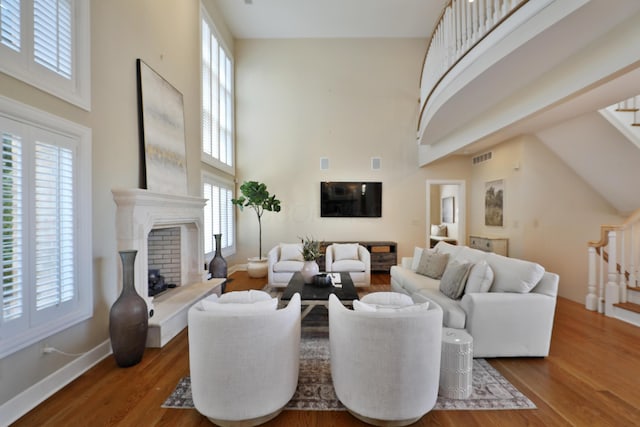 living area with wood finished floors, a high ceiling, and a fireplace with raised hearth