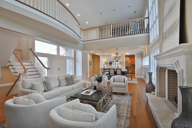 living area with wood finished floors, baseboards, stairs, a towering ceiling, and a notable chandelier