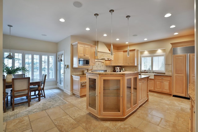 kitchen with backsplash, light brown cabinets, premium range hood, built in appliances, and stone tile flooring