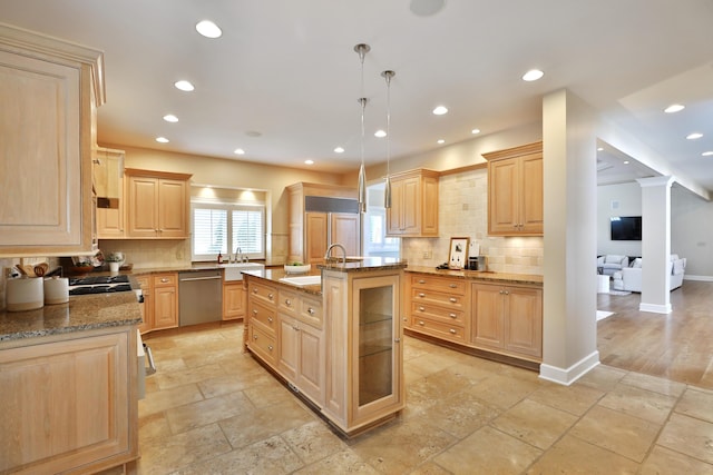 kitchen with a sink, light stone counters, light brown cabinets, and stainless steel appliances