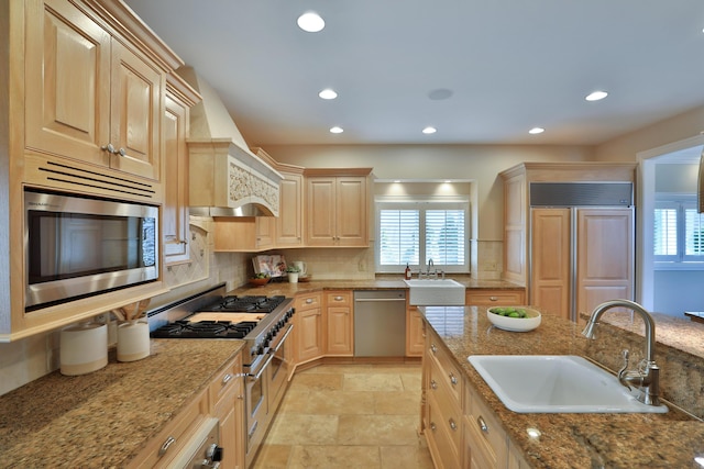 kitchen featuring a sink, built in appliances, custom exhaust hood, and light brown cabinetry