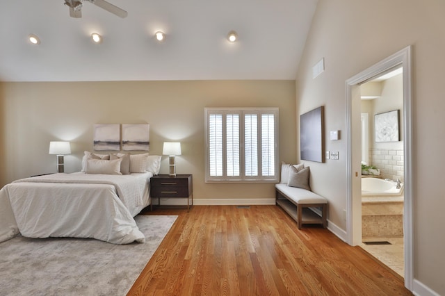 bedroom with visible vents, ensuite bath, wood finished floors, baseboards, and vaulted ceiling