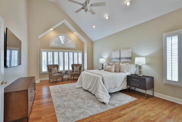 bedroom with baseboards, multiple windows, light wood-style floors, and high vaulted ceiling