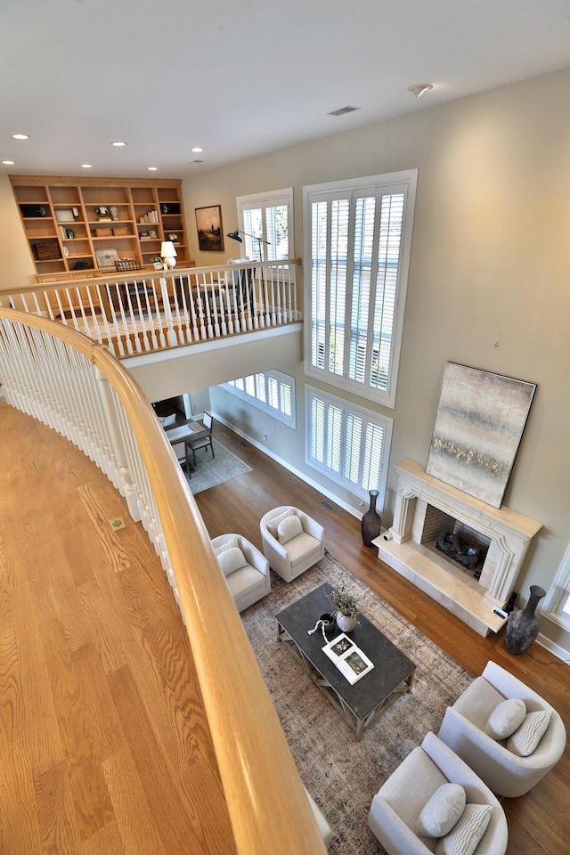 living room featuring a tiled fireplace, recessed lighting, wood finished floors, and visible vents