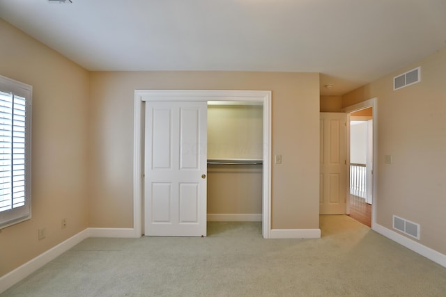 unfurnished bedroom featuring visible vents, light colored carpet, and baseboards