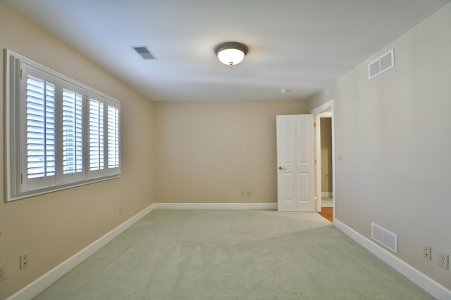 spare room with visible vents, carpet, and baseboards