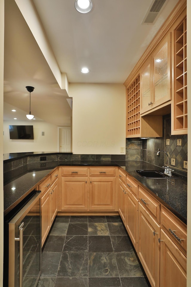 kitchen featuring visible vents, backsplash, beverage cooler, dark stone counters, and a sink