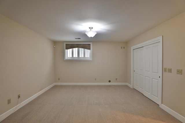 spare room featuring visible vents, baseboards, and light carpet