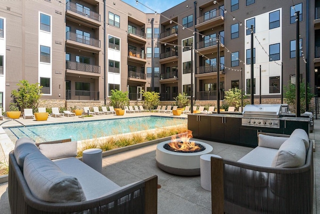 view of pool with a patio area, a grill, and a fire pit