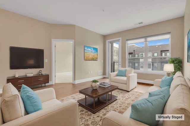 living area featuring baseboards, visible vents, and wood finished floors