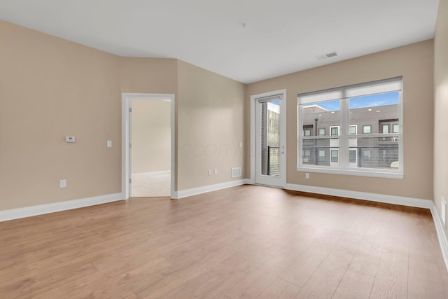 empty room featuring light wood-type flooring, visible vents, and baseboards