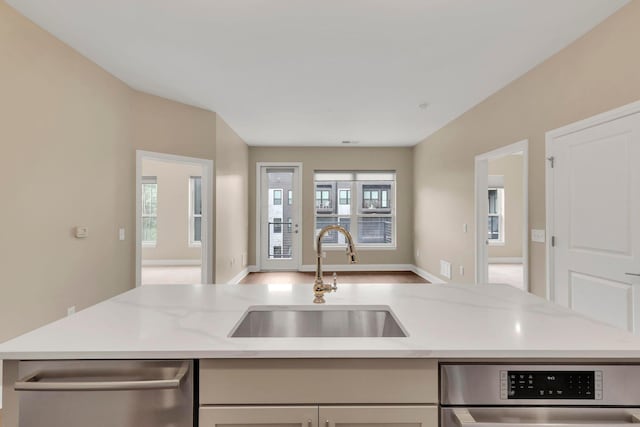 kitchen featuring open floor plan, oven, a sink, light stone countertops, and stainless steel dishwasher