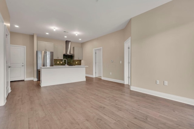 unfurnished living room featuring recessed lighting, a sink, light wood-style flooring, and baseboards