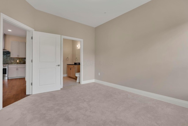 unfurnished bedroom with carpet floors, connected bathroom, and baseboards