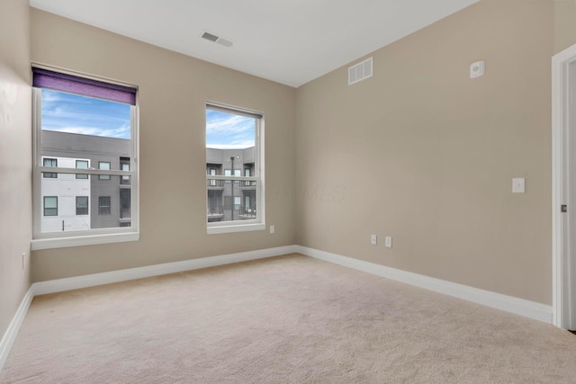 carpeted spare room with visible vents and baseboards